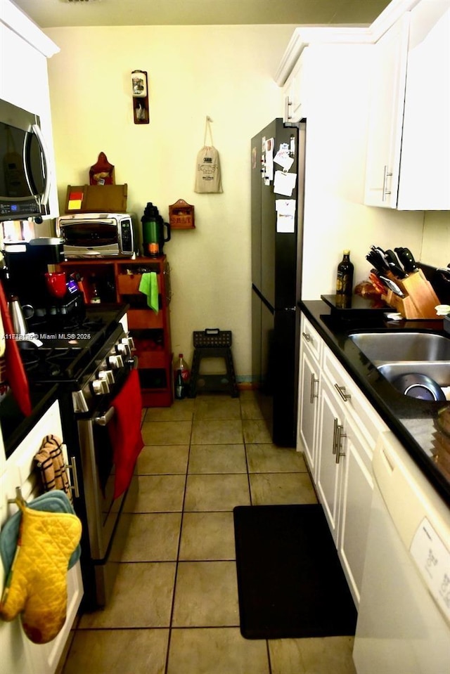 kitchen with light tile patterned flooring, stainless steel appliances, sink, and white cabinets