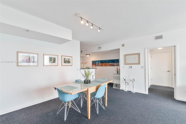 dining space featuring rail lighting and dark carpet