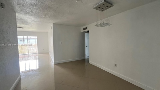 spare room with a textured ceiling and light tile patterned floors