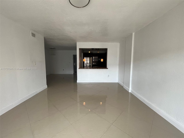 unfurnished living room featuring a textured ceiling and tile patterned flooring