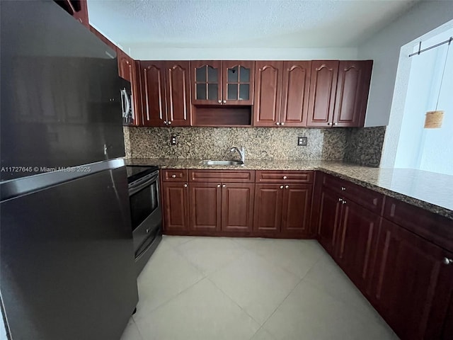 kitchen with light stone countertops, stainless steel appliances, decorative backsplash, sink, and kitchen peninsula