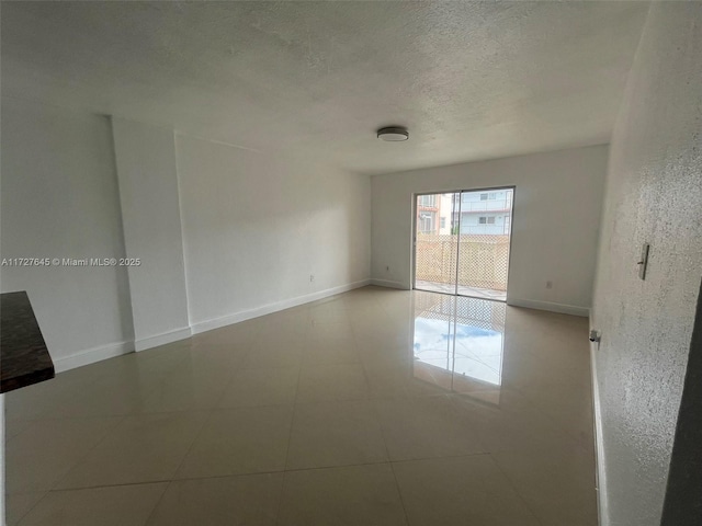 unfurnished room featuring a textured ceiling and light tile patterned floors