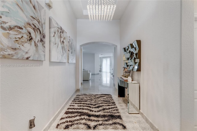 corridor with an inviting chandelier and a high ceiling