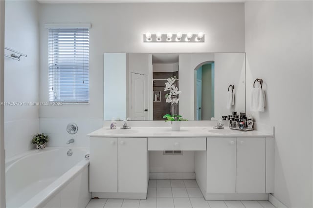 bathroom with tiled bath, vanity, and tile patterned flooring