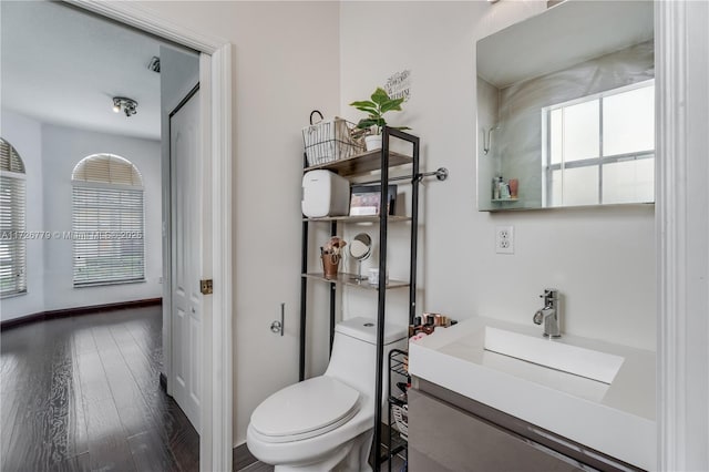 bathroom with toilet, hardwood / wood-style floors, and vanity