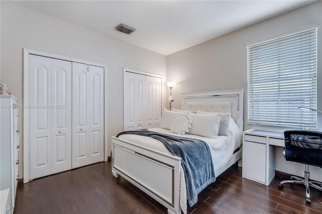 bedroom with dark hardwood / wood-style floors and two closets