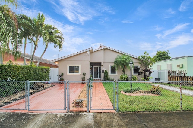 view of front of house featuring a fenced front yard, a gate, a front lawn, and stucco siding