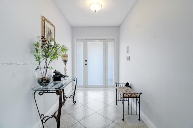 entryway featuring a textured ceiling, baseboards, and light tile patterned floors