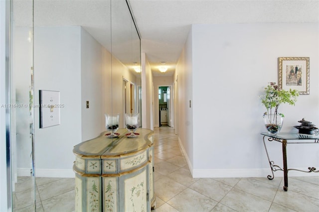 hallway featuring light tile patterned flooring and baseboards