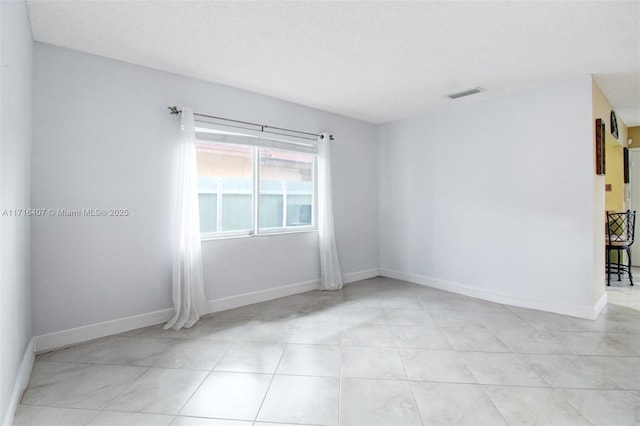 empty room featuring baseboards and visible vents