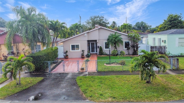 view of front of home with driveway, a fenced front yard, a gate, a front yard, and stucco siding