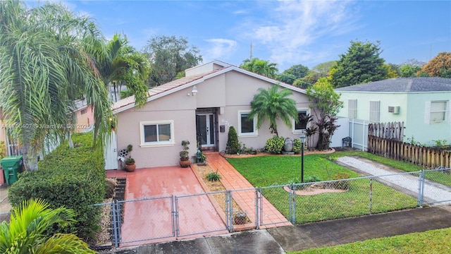 view of front facade featuring a fenced front yard, a gate, a front lawn, and stucco siding