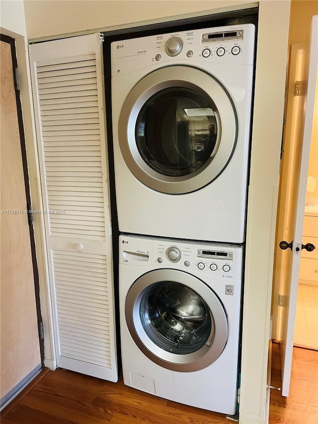 washroom with stacked washer and clothes dryer and hardwood / wood-style flooring