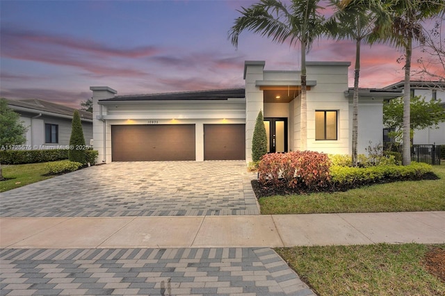 contemporary home with a garage, decorative driveway, and stucco siding