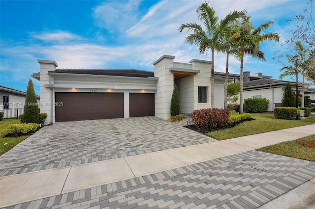 view of front of home with a garage, a front lawn, decorative driveway, and fence