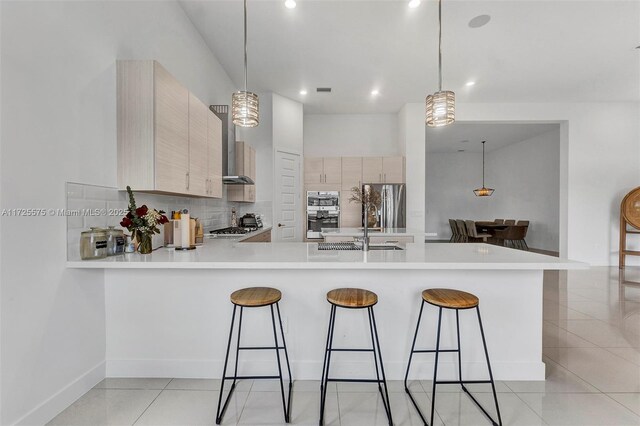 kitchen featuring pendant lighting, light brown cabinets, and kitchen peninsula