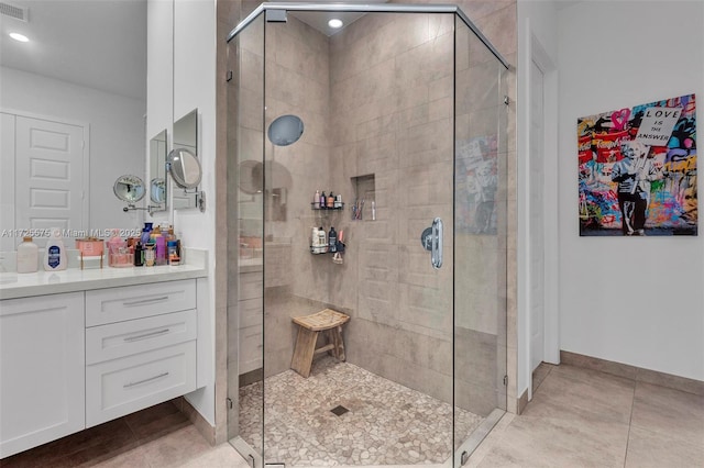 bathroom featuring a stall shower, vanity, baseboards, and tile patterned floors