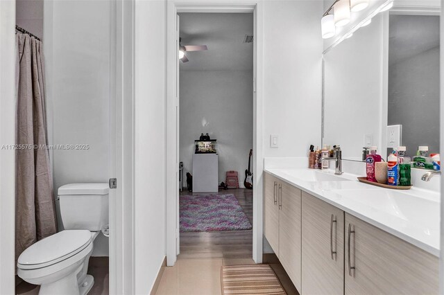 bathroom with toilet, vanity, ceiling fan, and hardwood / wood-style floors