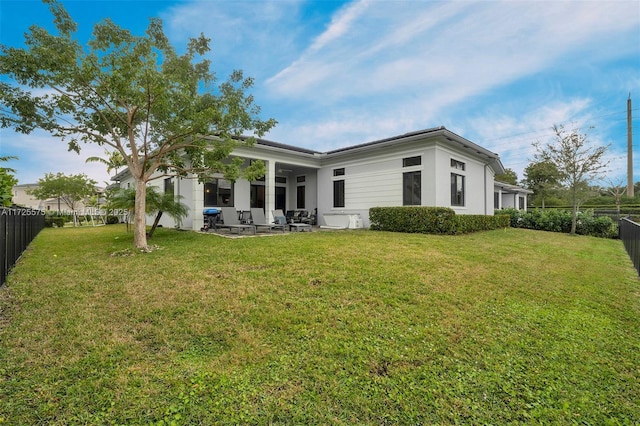 rear view of house featuring a patio, a lawn, and a fenced backyard