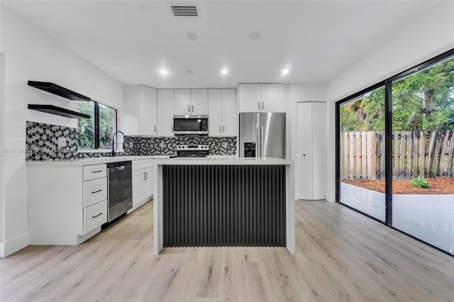 kitchen featuring light hardwood / wood-style floors, appliances with stainless steel finishes, white cabinetry, and a center island