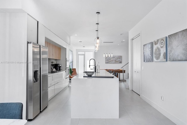 kitchen with stainless steel refrigerator with ice dispenser, pendant lighting, white cabinets, and an island with sink