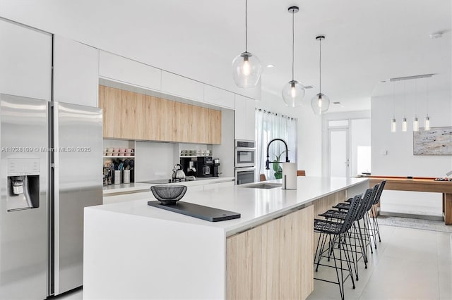 kitchen with sink, white cabinetry, stainless steel appliances, and an island with sink