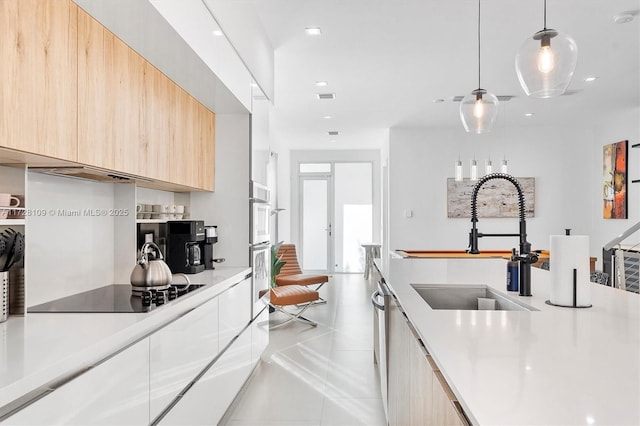 kitchen featuring appliances with stainless steel finishes, light brown cabinets, sink, hanging light fixtures, and light tile patterned floors