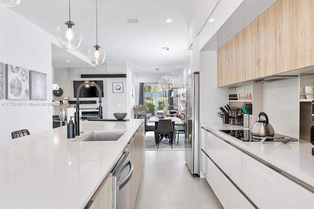 kitchen featuring appliances with stainless steel finishes, white cabinetry, light brown cabinets, sink, and hanging light fixtures