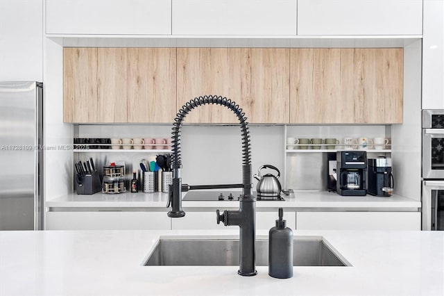 room details with white cabinets, light brown cabinetry, appliances with stainless steel finishes, and sink