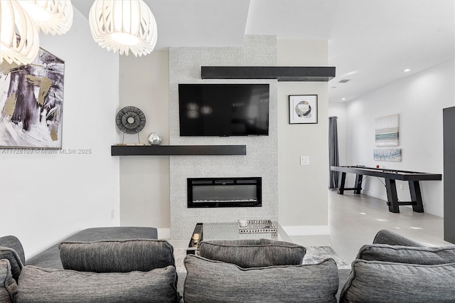 living room featuring a large fireplace, concrete floors, and a chandelier