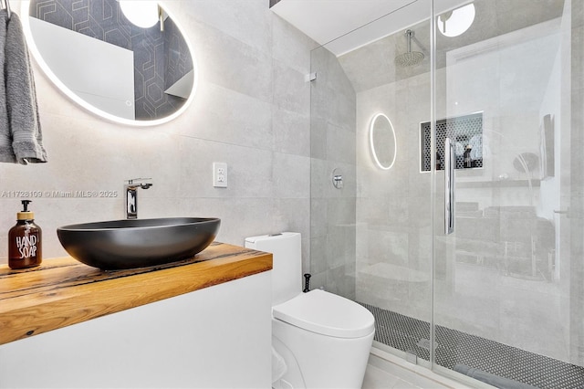 bathroom featuring toilet, tile walls, a shower with shower door, and vanity