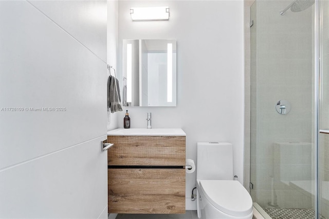 bathroom with toilet, vanity, and a shower with shower door