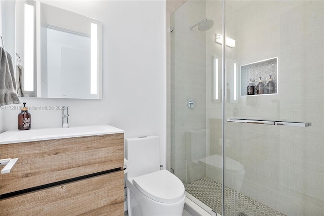 bathroom featuring toilet, a shower with door, and vanity