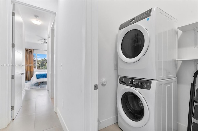 clothes washing area featuring ceiling fan, light tile patterned floors, and stacked washer and dryer