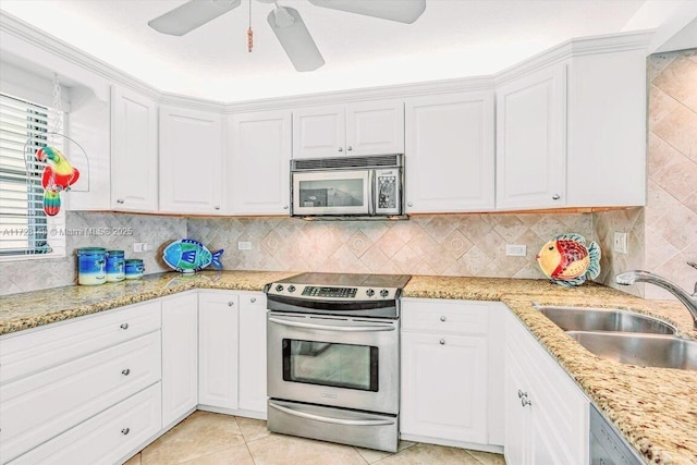 kitchen featuring appliances with stainless steel finishes, white cabinetry, sink, decorative backsplash, and light tile patterned floors