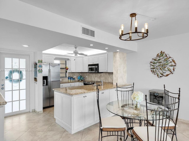 kitchen with stainless steel appliances, light stone counters, tasteful backsplash, white cabinets, and kitchen peninsula