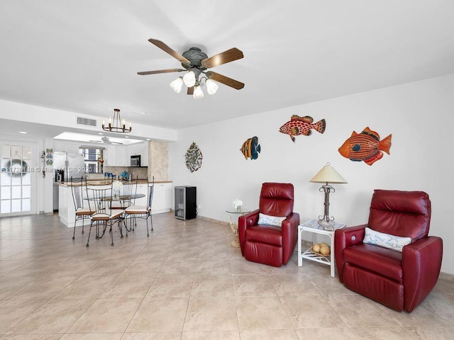 living room featuring ceiling fan with notable chandelier and light tile patterned flooring