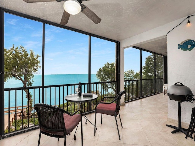 sunroom with a water view and ceiling fan