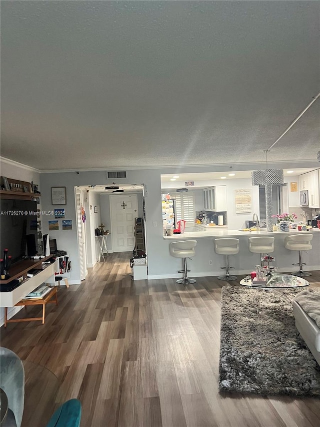 living room featuring a textured ceiling, ornamental molding, and hardwood / wood-style floors