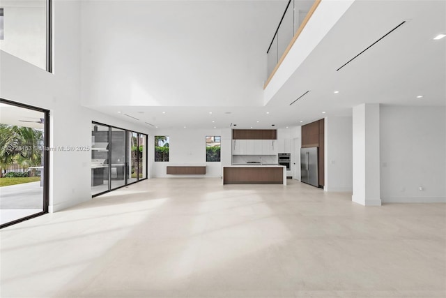 unfurnished living room featuring a towering ceiling