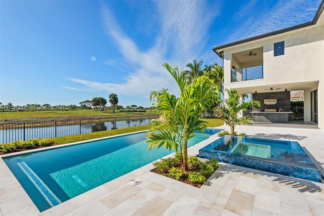 view of swimming pool with ceiling fan, a patio area, a water view, and an in ground hot tub