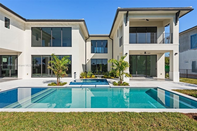 back of house with ceiling fan, a patio area, a pool with hot tub, and a balcony