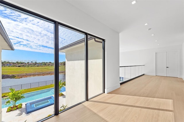 doorway to outside featuring a water view and light hardwood / wood-style floors