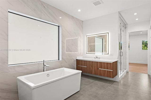 bathroom with shower with separate bathtub, vanity, and tile walls