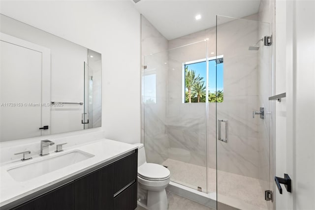 bathroom featuring toilet, vanity, and a shower with door