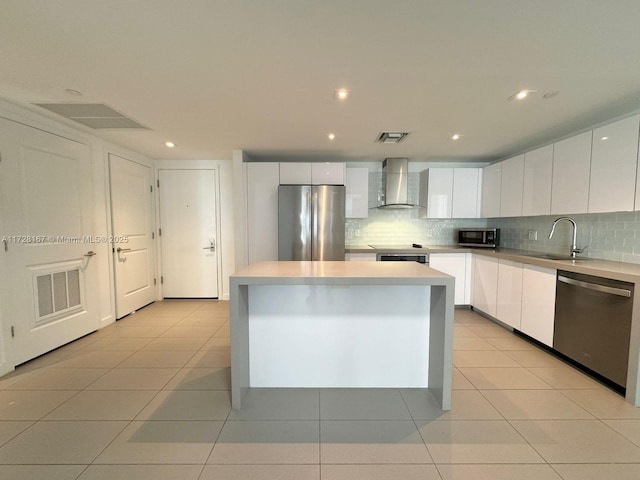 kitchen featuring white cabinetry, wall chimney range hood, appliances with stainless steel finishes, and a center island