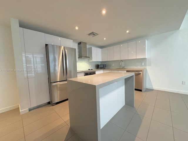 kitchen featuring white cabinets, a center island, wall chimney exhaust hood, stainless steel appliances, and sink