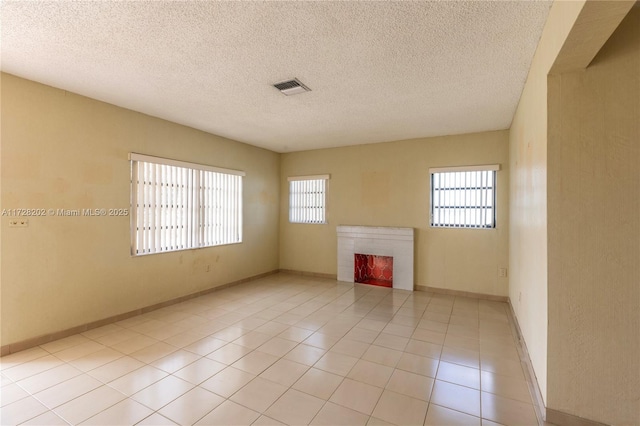 unfurnished living room featuring plenty of natural light, a textured ceiling, and light tile patterned flooring