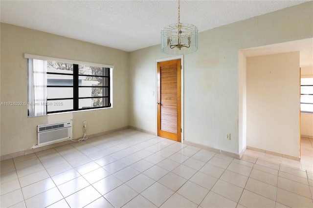 tiled spare room with a chandelier, a textured ceiling, and a wall unit AC