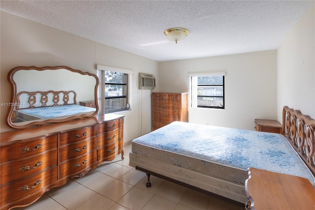 bedroom with light tile patterned flooring, a textured ceiling, and a wall unit AC